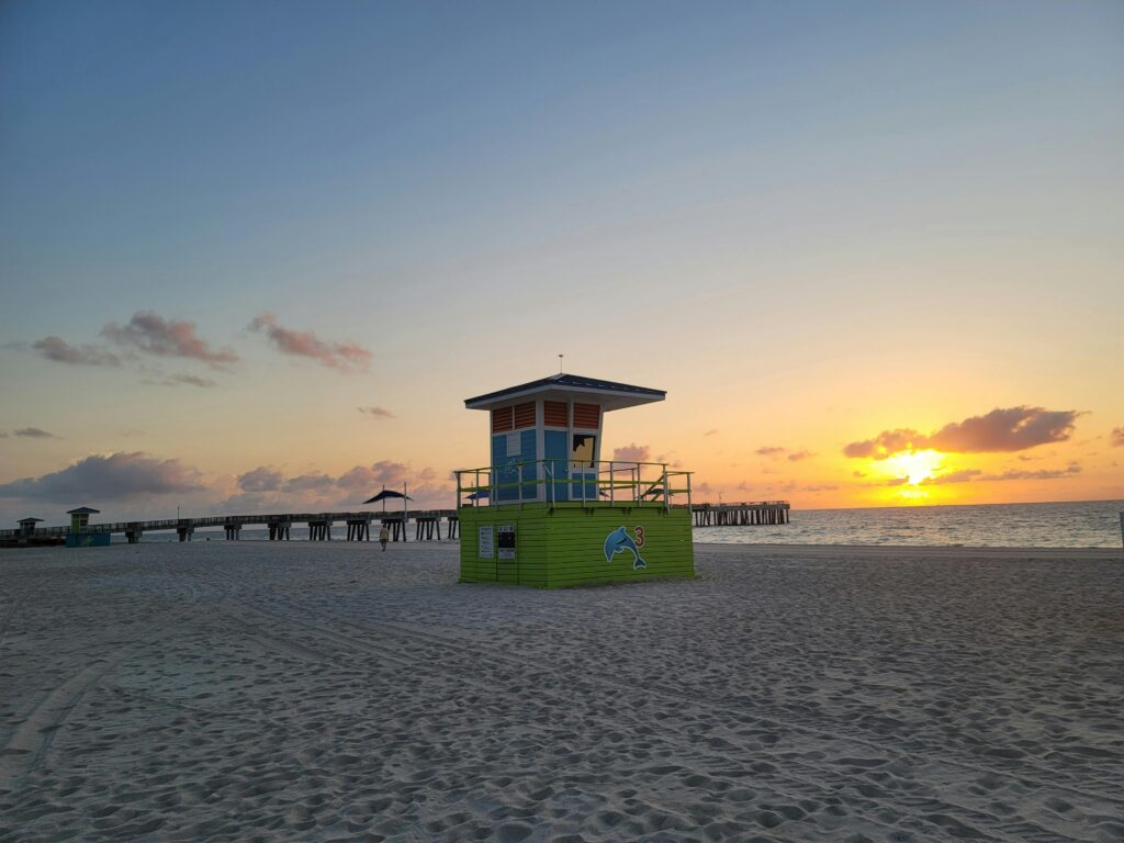 Colorful lifeguard tower at Pompano Beach during a serene sunrise over the ocean.