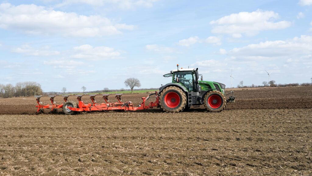 A tractor is seen plowing a field in Geesthacht, Germany, under a clear blue sky.