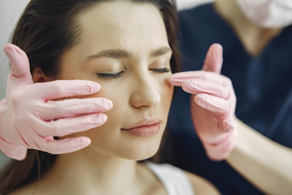 Close-up of a woman with eyes closed receiving facial care in a beauty clinic indoors.
