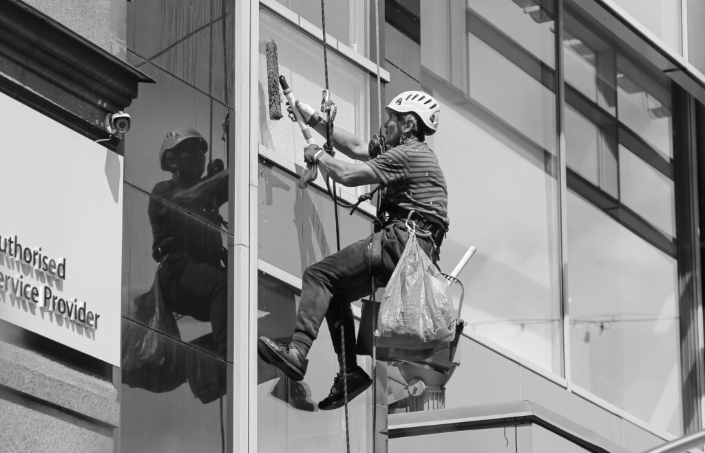 Professional window cleaner working on a skyscraper facade in Riga.