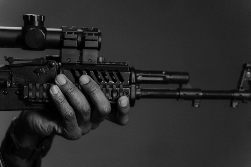 Monochrome close-up of a hand holding a rifle, emphasizing tactical equipment.