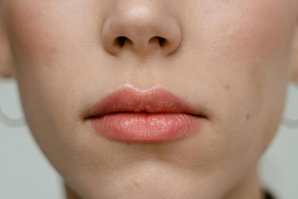 A detailed close-up of a woman's lips showcasing pink lipstick and subtle makeup.