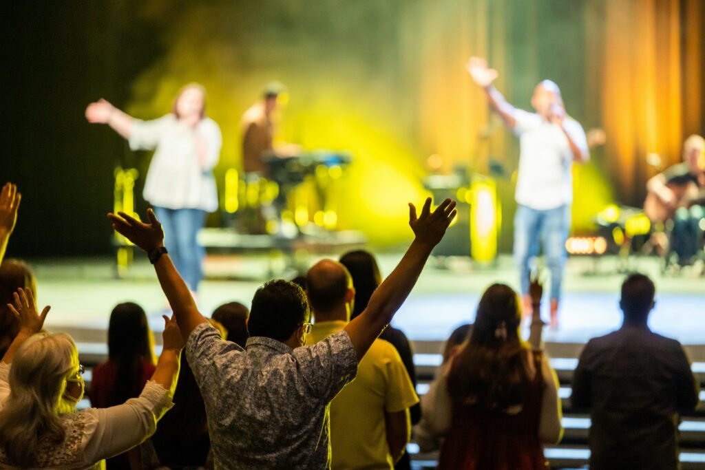 Excited concert audience with hands raised, enjoying the live music performance indoors.