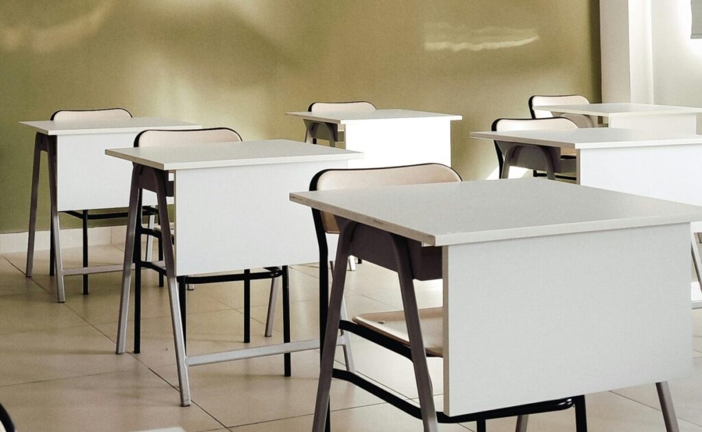Modern classroom interior with desks and chairs, showcasing clean design and ample natural light.