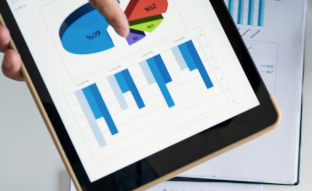 Business professionals handshake over graphs and charts in a corporate setting, symbolizing successful negotiation and agreement.